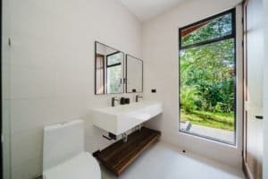 Contemporary bathroom with large window overlooking lush greenery in Dominical.