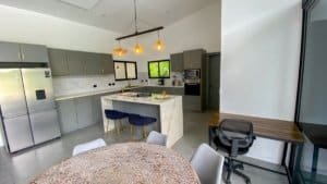 Spacious modern kitchen with gray cabinets, marble island, and dining area in Dominical.