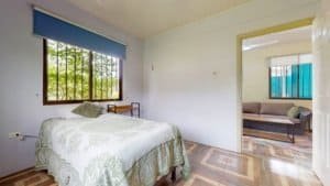 Cozy bedroom with large window and view in Dominical real estate.