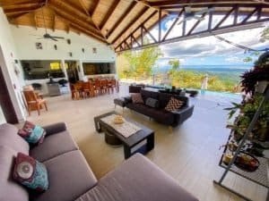 Spacious living room with ocean view, high wooden ceiling, and modern furniture.