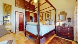 Elegant bedroom with four-poster bed, antique furniture, and tropical decor.