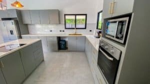 Contemporary kitchen with gray cabinets, white countertops, and stainless appliances.