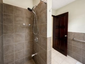 Bathroom with shower and brown tiled walls in Dominical real estate property.