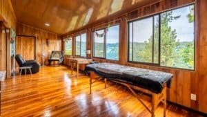 Cozy mountain home interior with large windows overlooking lush greenery and mountains.