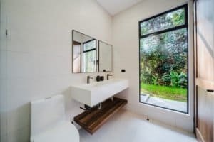 Bright modern bathroom with large window overlooking lush greenery.
