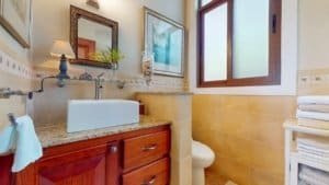 Interior view of a bathroom with a white sink, wooden cabinets, and a window in Costa Rica.