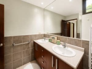 Clean bathroom with double sinks, mirror, and neutral decor in Costa Rica.
