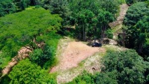 A cleared 1.8-acre lot surrounded by lush green trees and mountain scenery.