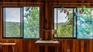 Interior view of a wooden mountain home with large windows and scenic forest views.