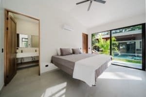Contemporary bedroom with large glass doors overlooking pool and garden.