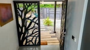 Modern entrance with decorative metal tree design and pathway to garden.