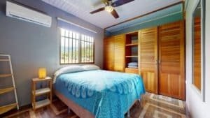 Cozy bedroom with wooden closet and large window in Dominical.