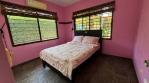 Comfortable bedroom with pink walls and large windows in Dominical.