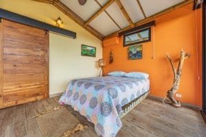 Bedroom with colorful quilt, wooden accents, and mountain view window.