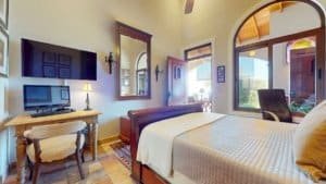 Comfortable bedroom with large windows and tropical scenery outside.