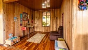 Interior of a mountain home with wooden walls, colorful decor, and a window view.