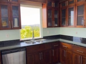 Kitchen with wooden cabinets, granite countertops, and mountain view through window.