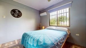 Cozy bedroom with large window, air conditioning, and wooden flooring in Dominical.