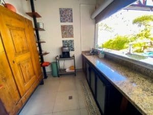 Interior of kitchen with granite counter and large window overlooking greenery.