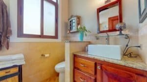 Bathroom with wooden vanity, white sink, and natural light in Costa Rica.