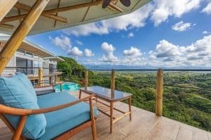 Balcony with seating overlooking lush green mountains and blue sky in Dominical.