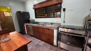 Kitchen with wooden cabinets, stove, and refrigerator in Dominical real estate property.