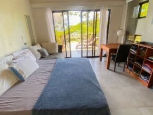 Bedroom with balcony overlooking lush greenery and ocean in Dominical.