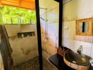 Bathroom with stone sink, mirror, and outdoor view in Dominical.