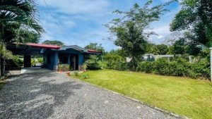 Costa Rican home with private pool, lush garden, and driveway.