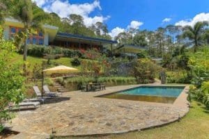 Stunning mountain view home with pool, lush gardens, and tropical landscape.