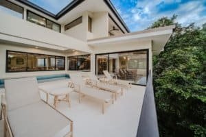 Modern balcony with lounge chairs overlooking lush jungle and ocean in Costa Rica.