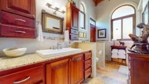 Spacious bathroom with wooden cabinets, large mirror, and natural light in Costa Rica.