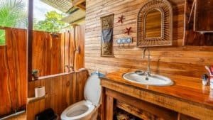 Wooden bathroom with toilet and sink in a mountain home near Nauyaca Waterfalls.