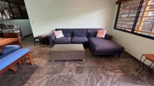 Living room with dark sofa, wicker coffee table, and large windows in Dominical.