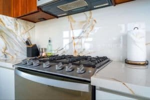 Contemporary kitchen with marble backsplash, stove, and paper towel holder.