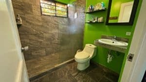 Modern bathroom with green walls, shower, toilet, and sink in Dominical.
