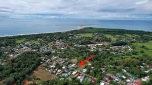 Aerial view of Dominical with houses, greenery, and ocean in the background.