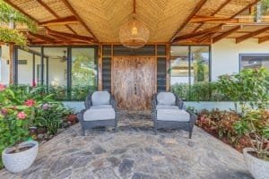 Elegant estate entrance with two chairs, lush plants, and wooden accents.