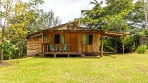 Rustic wooden house with porch surrounded by lush greenery in Dominical, Costa Rica.