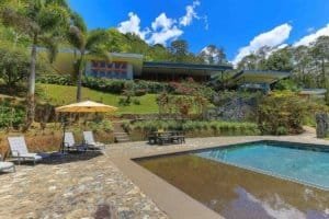 Modern mountain home with pool, lush greenery, and panoramic views in Dominical.