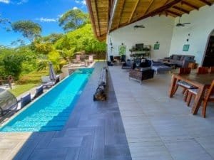 Spacious outdoor living area with pool and lush tropical scenery.