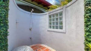 Tropical outdoor shower with curved wall and glass block window.