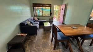 Living room with sofa, coffee table, and open door to outdoor area in Dominical.