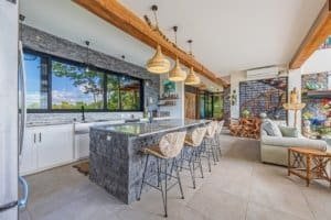 Modern kitchen with mountain views, stone island, and cozy living area in Dominical.