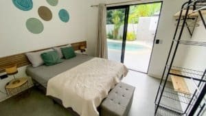 Comfortable bedroom with sliding glass door to pool and tropical garden.