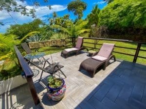 Balcony with lounge chairs overlooking lush tropical landscape and ocean view.