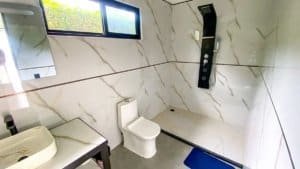 Contemporary bathroom with marble walls, toilet, and shower in Costa Rica.