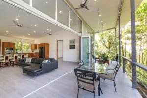 Spacious living room with large glass doors and balcony overlooking nature.