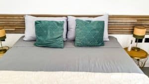 Comfortable bed with teal pillows and wooden headboard in a stylish bedroom.