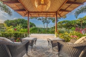 Covered outdoor lounge with mountain views and lush garden in Dominical.